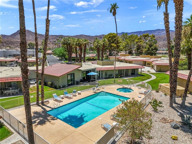 community pool featuring a community hot tub, fence, a mountain view, and a patio