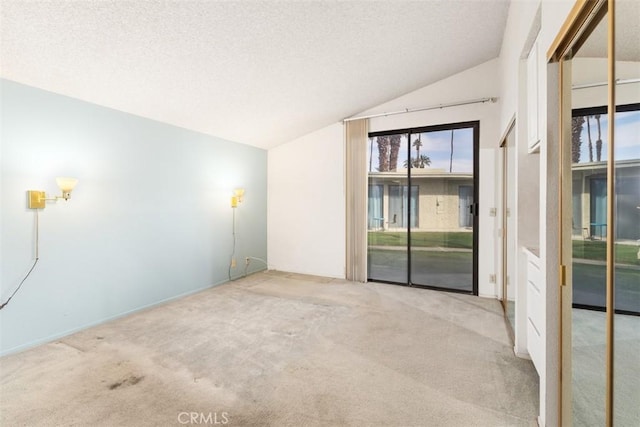 carpeted spare room with lofted ceiling and a textured ceiling