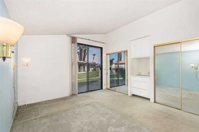 spare room featuring light carpet and vaulted ceiling