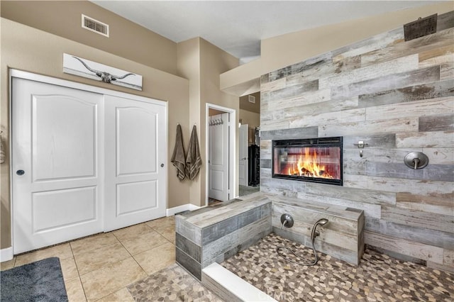 bathroom with a fireplace, tile patterned floors, and wooden walls