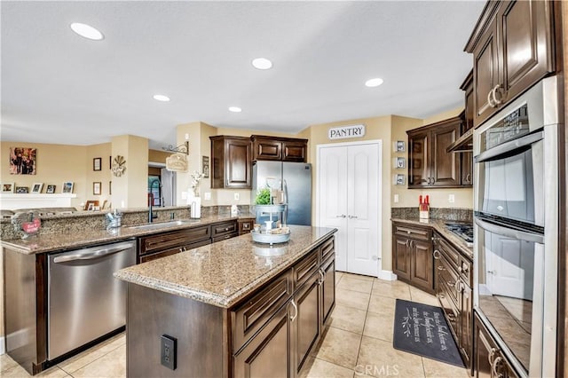 kitchen with stainless steel appliances, a center island, sink, and light tile patterned floors