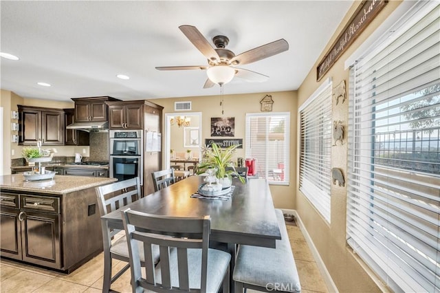 kitchen with appliances with stainless steel finishes, a center island, light tile patterned floors, ceiling fan, and dark brown cabinetry