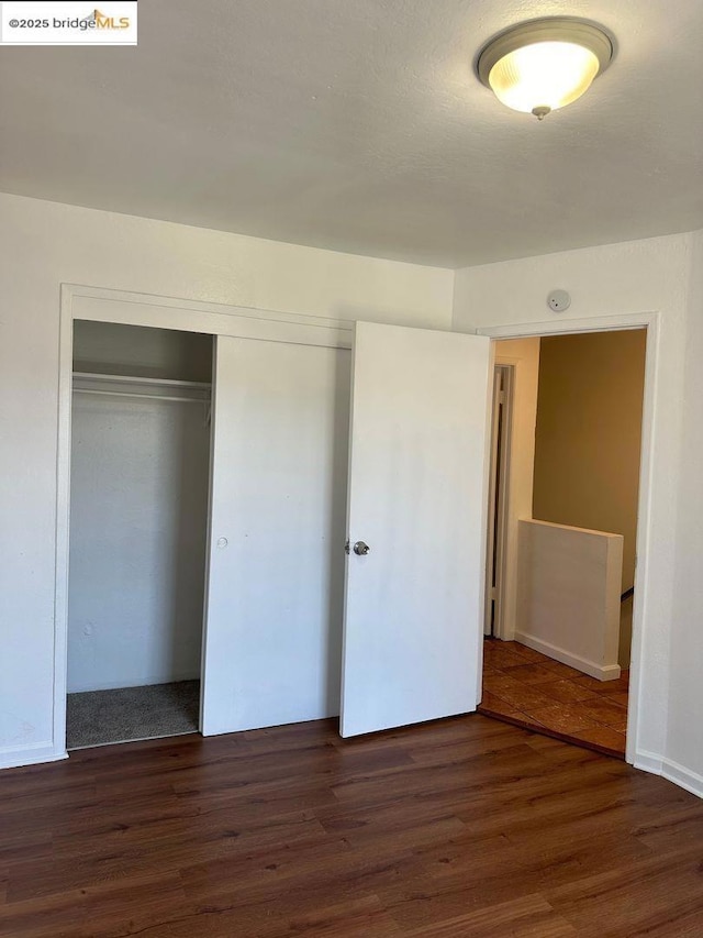 unfurnished bedroom featuring dark hardwood / wood-style flooring and a closet