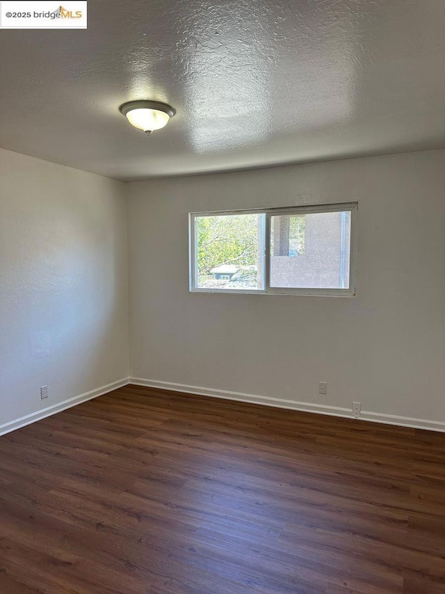 empty room featuring dark hardwood / wood-style floors and a textured ceiling