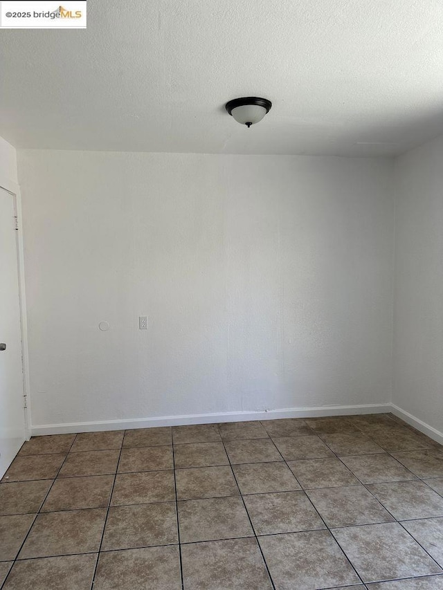 tiled empty room with a textured ceiling