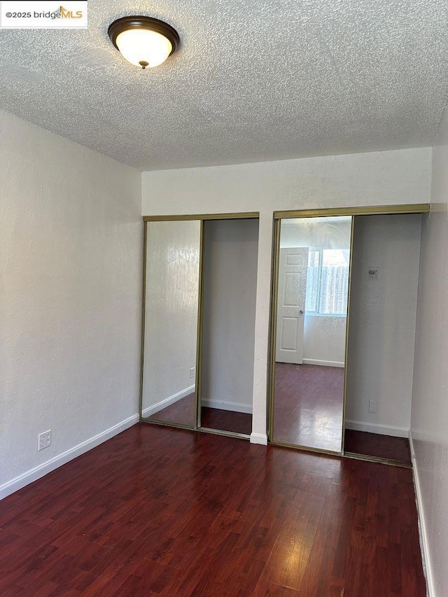 unfurnished bedroom featuring a textured ceiling and dark hardwood / wood-style flooring