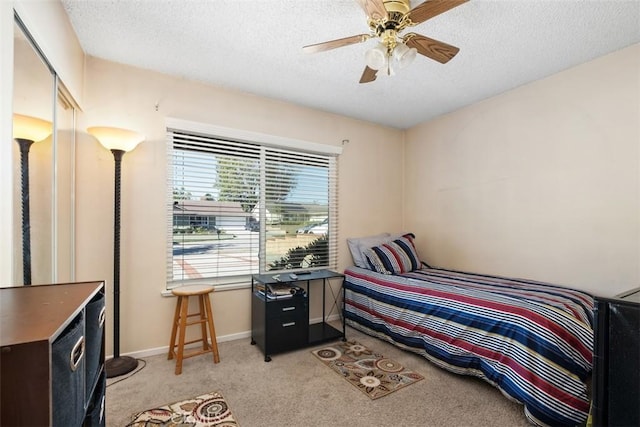 carpeted bedroom featuring ceiling fan, a closet, and a textured ceiling