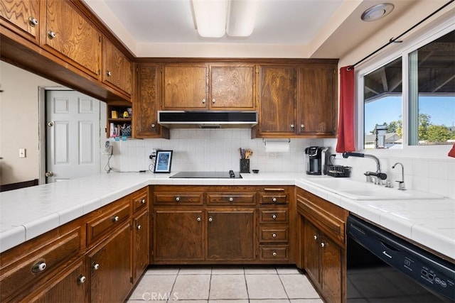 kitchen featuring tasteful backsplash, light tile patterned flooring, tile counters, and black appliances