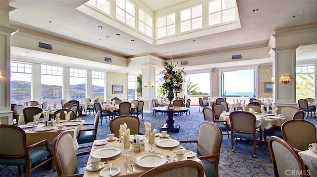 dining space featuring crown molding, a towering ceiling, a mountain view, and decorative columns