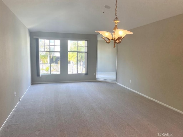 unfurnished room with carpet flooring and a notable chandelier