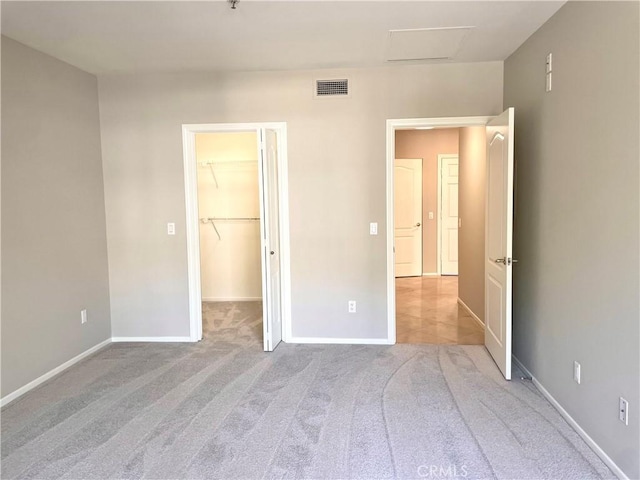 unfurnished bedroom featuring a spacious closet, light carpet, and a closet