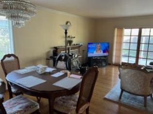 dining space with hardwood / wood-style flooring, a healthy amount of sunlight, and a chandelier