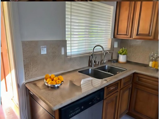 kitchen with tasteful backsplash, stainless steel dishwasher, light stone countertops, and sink