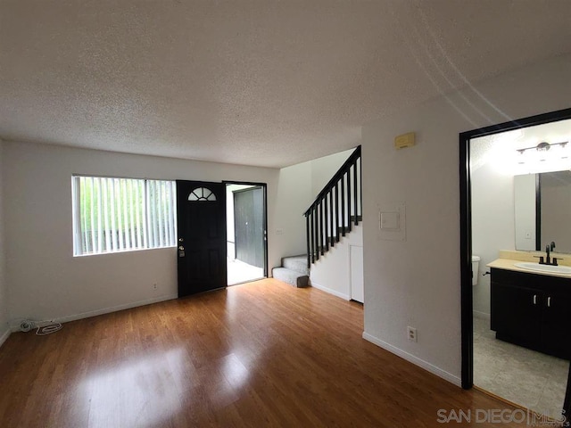 foyer with hardwood / wood-style flooring, sink, and a textured ceiling