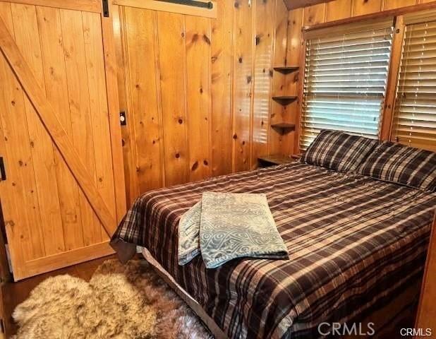 bedroom featuring wooden walls and a barn door