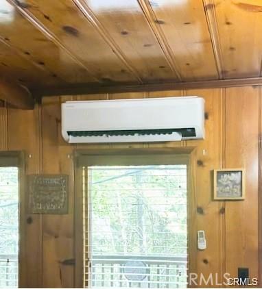 interior space with wood ceiling, a wall mounted air conditioner, and wood walls