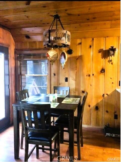 dining room with wood ceiling, hardwood / wood-style flooring, and wood walls