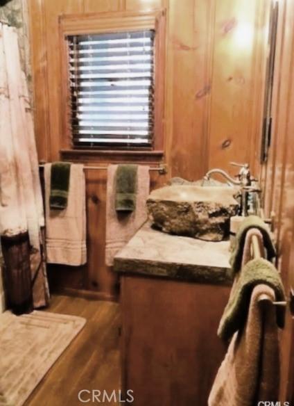 bathroom with sink, hardwood / wood-style floors, and wooden walls