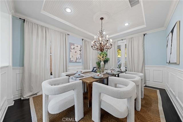 dining room featuring a tray ceiling, crown molding, dark wood-type flooring, and a chandelier