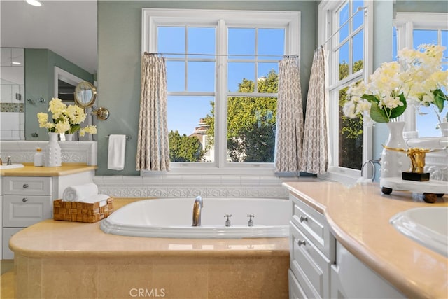 bathroom with vanity and tiled bath