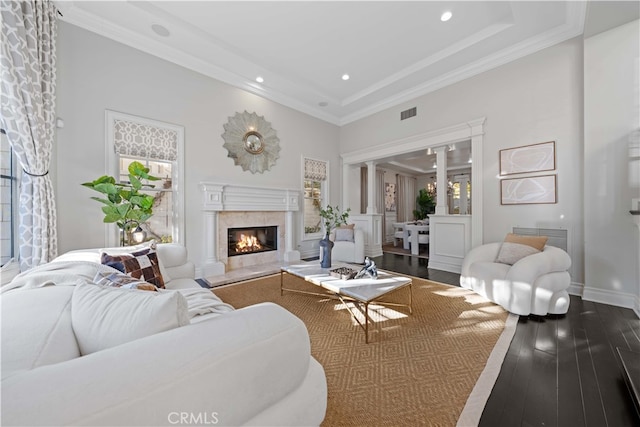 living room featuring hardwood / wood-style floors, ornamental molding, decorative columns, and a premium fireplace