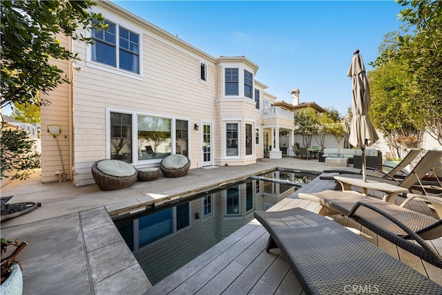 wooden deck with a swimming pool, an outdoor hangout area, and a patio area