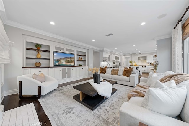 living room featuring crown molding, wood-type flooring, and built in features