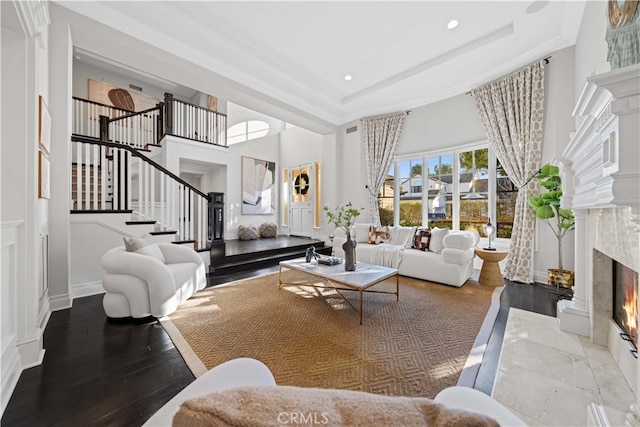 living room with a high end fireplace, a raised ceiling, and wood-type flooring