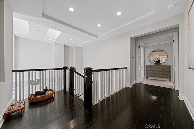 corridor with a raised ceiling, dark wood-type flooring, and a skylight