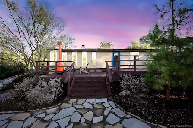 back house at dusk with a wooden deck