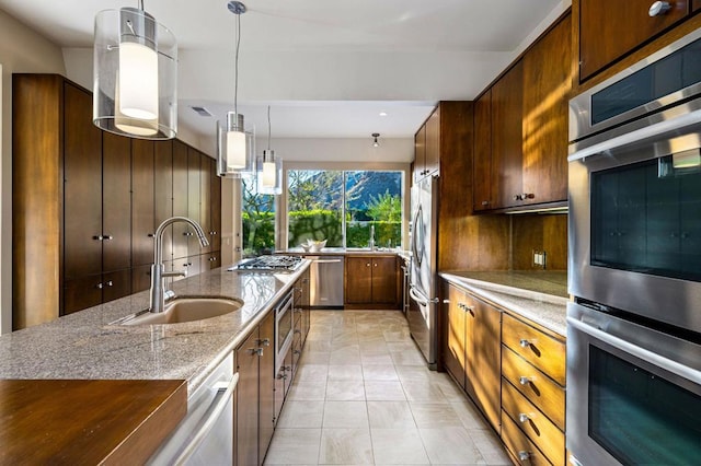 kitchen featuring pendant lighting, sink, backsplash, light stone counters, and stainless steel appliances