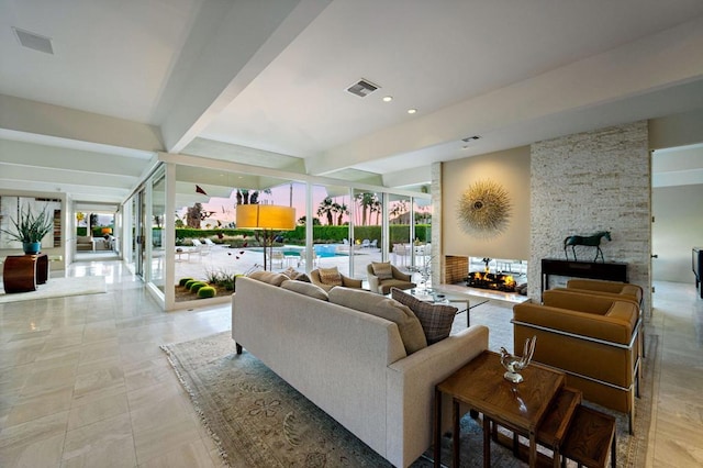 living room featuring beamed ceiling and a stone fireplace