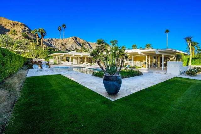 back of property featuring a mountain view, a yard, and a patio