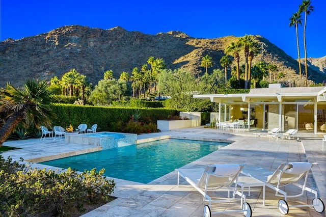 view of pool with an in ground hot tub, a mountain view, and a patio