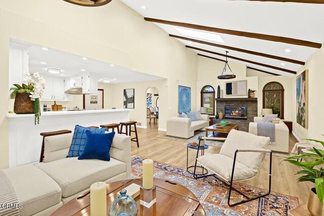 living room featuring a fireplace, beam ceiling, and light hardwood / wood-style flooring