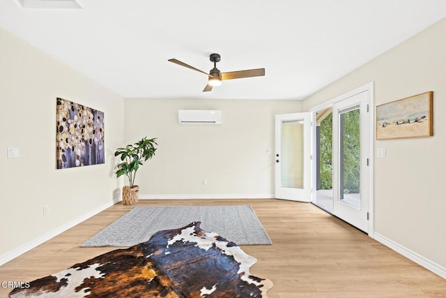 interior space featuring a wall mounted air conditioner, light hardwood / wood-style flooring, and ceiling fan