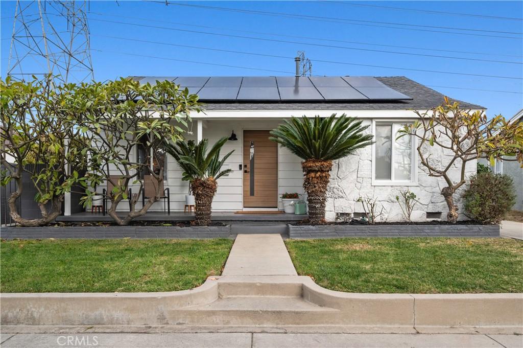 view of front facade with covered porch, a front yard, and solar panels