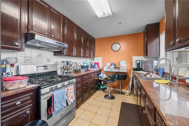 kitchen with stainless steel gas stove, tasteful backsplash, dark brown cabinetry, and light tile patterned flooring