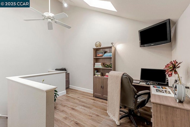 home office featuring ceiling fan, light hardwood / wood-style floors, and vaulted ceiling with skylight