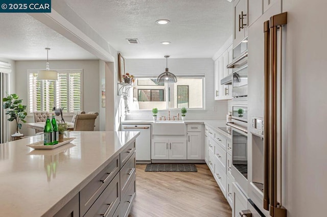 kitchen with hanging light fixtures, sink, white cabinets, and white dishwasher