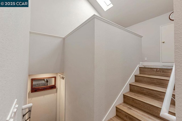 staircase featuring lofted ceiling with skylight