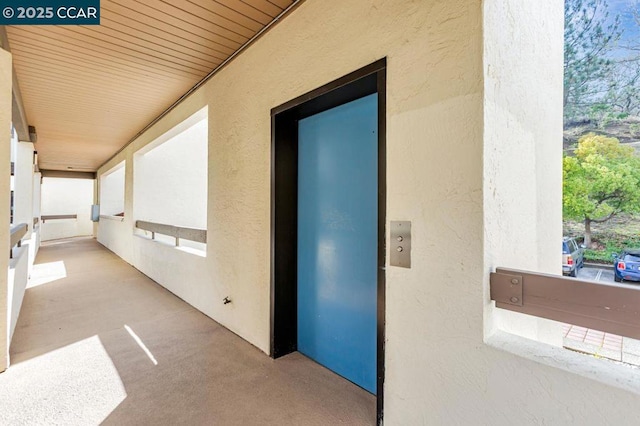 corridor with elevator and wooden ceiling