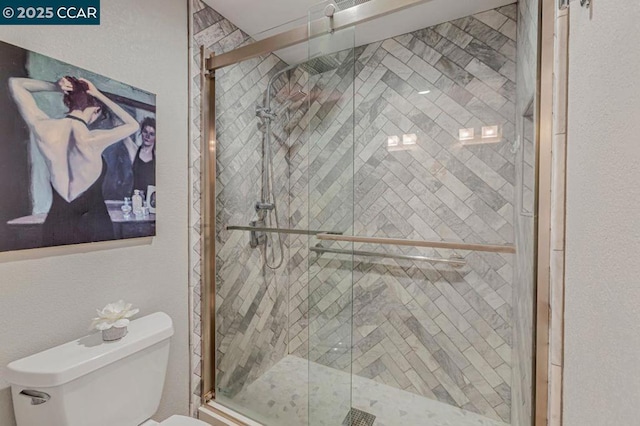 bathroom featuring a shower with shower door and toilet