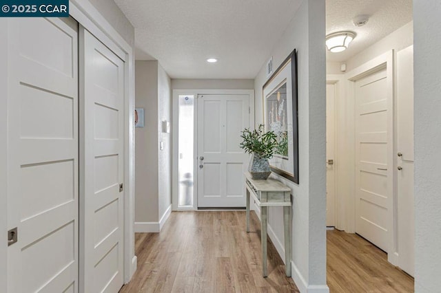 foyer entrance with a textured ceiling and light wood-type flooring