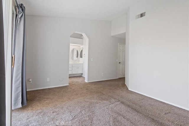 unfurnished bedroom featuring light carpet and ensuite bathroom