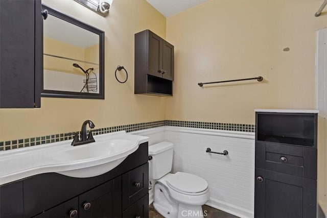 bathroom with vanity, toilet, and tile walls