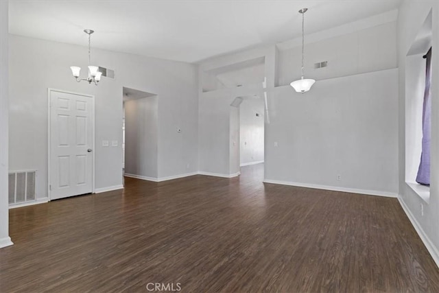 empty room with high vaulted ceiling, dark wood-type flooring, and a chandelier