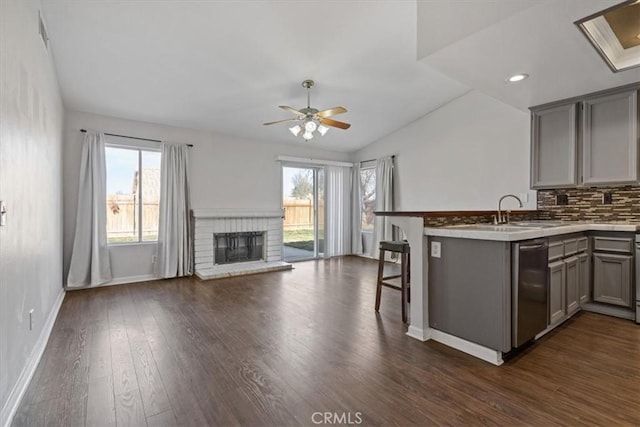 kitchen featuring tasteful backsplash, sink, gray cabinetry, a kitchen bar, and kitchen peninsula