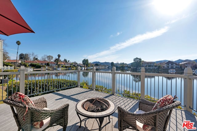 wooden deck with a water view and an outdoor fire pit