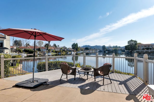 wooden deck featuring a water view and an outdoor fire pit